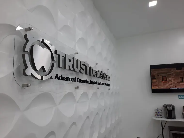 Logotipo dimensional en muro texturizado de recepción · TRUST Dental Care