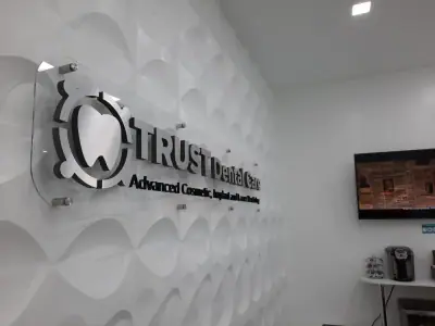 Dimensional logo on a textured reception wall · TRUST Dental Care