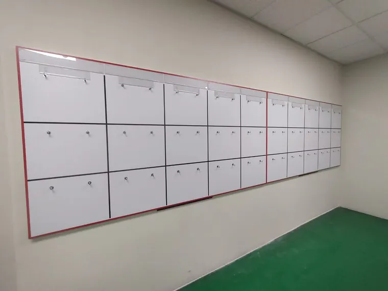 Muro de pizarras con ganchos para formatos, instalado en pasillo de planta